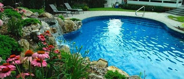 Free-form Vinly Pool: Vinyl-lined pools can be constructed in any shape, curve, or angle, which made it easier to fit a pool in this yard. By taking advantage of the property’s rising grade, Deck and Patio created a natural retaining wall, studded with gorgeous plantings, moss and river rock to hold back the rising soil. Added benefit: the sounds an added waterfall makes their long desired pool experience even better.