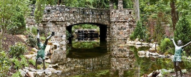 Large Reflecting Pond with Stone Bridge (Long Island/NY): The stone bridge with turret creates a stunning pond reflection in its crystal clear water. The water stays this way because we used a natural ecosystem to keep it clean. There is a large bog filter at the waterfall on one end, with a 3,000 gallon pondless reservoir with two 20,000 GPH pumps feeding the waterfall.